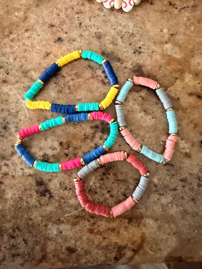 Four colorful clay bead bracelets arranged on stone